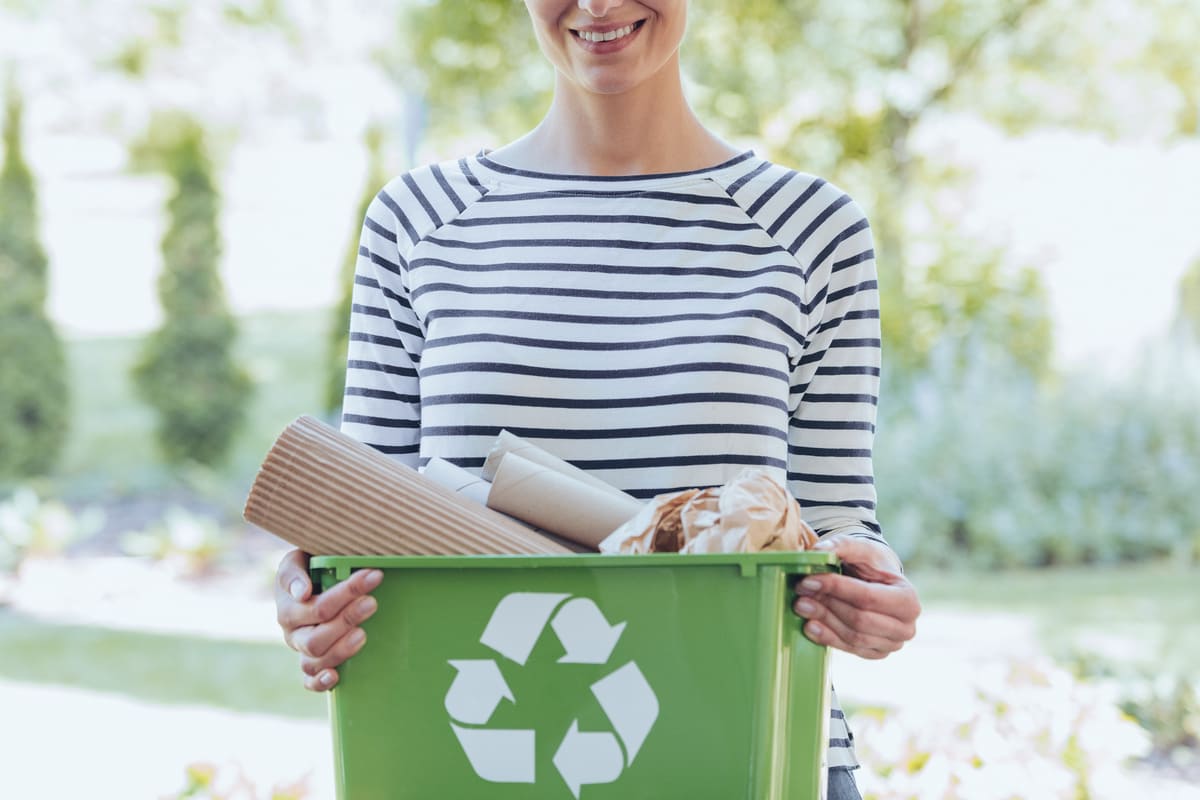femeie cu recipient reciclare hartie zambeste in gradina eco